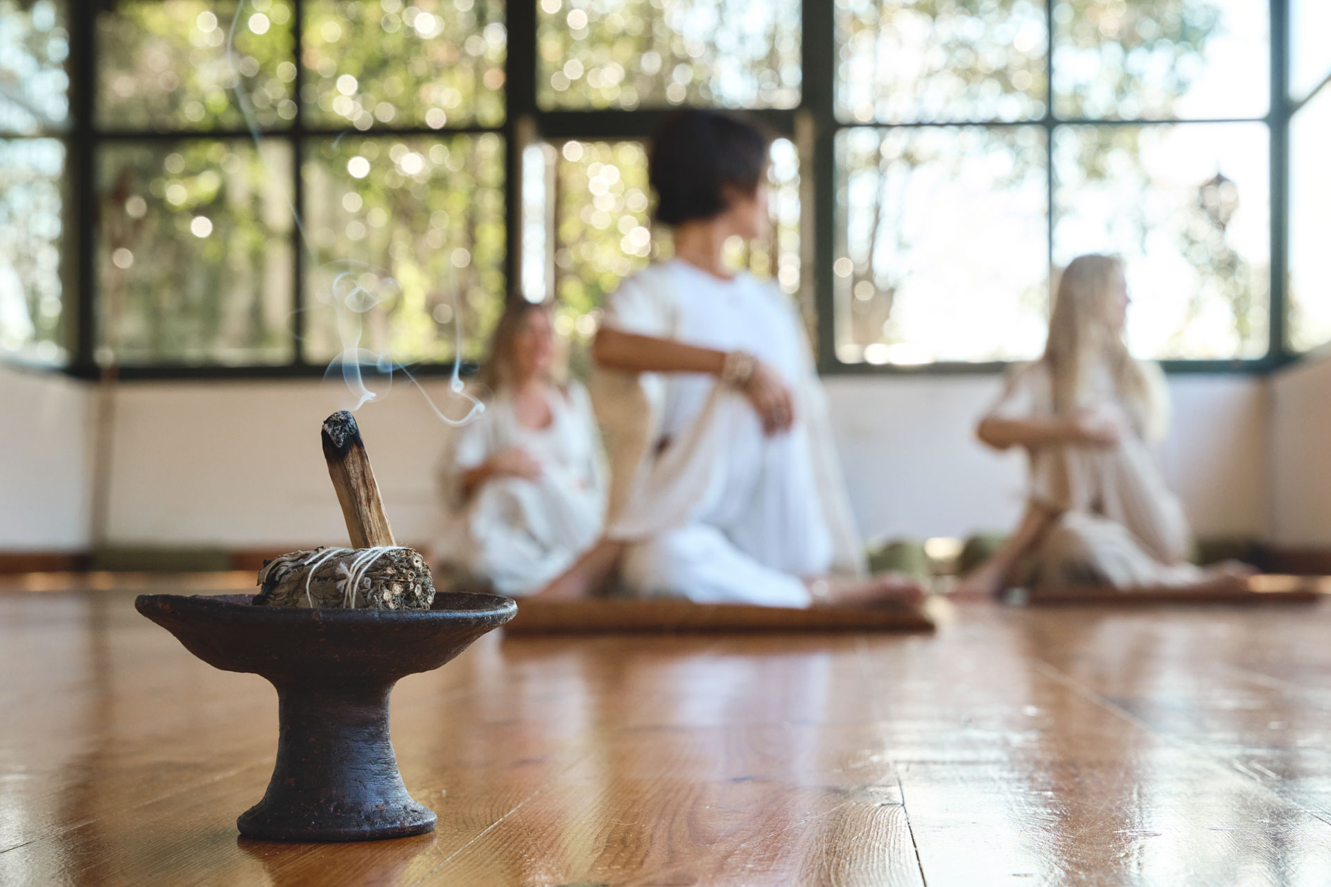 Sandalwood stick with meditating people group doing yoga on background.